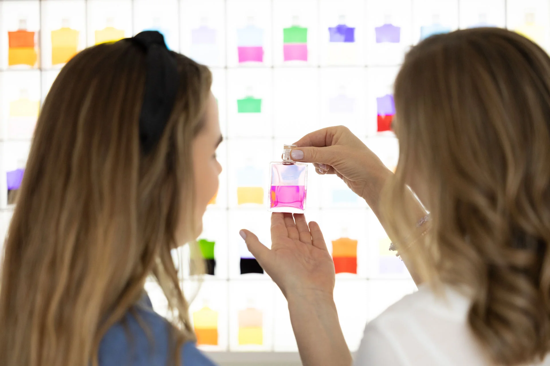 Patricia Maryriam und eine Kundin stehen vor dem Aura-Soma® Regal und betrachten eine Flasche