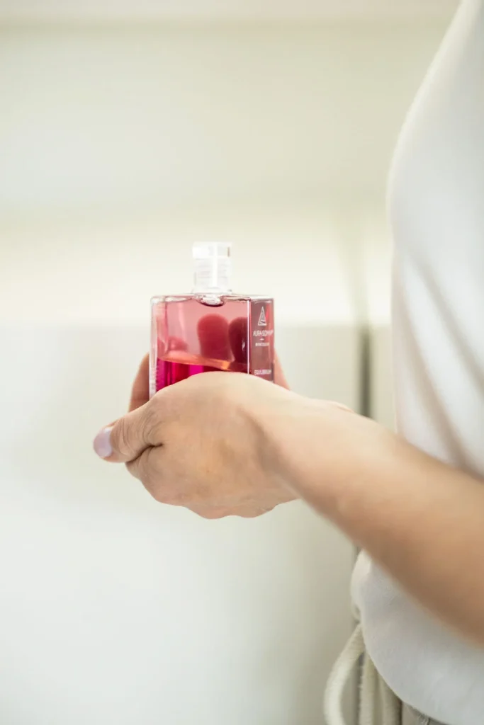 Rote Aura-Soma® Flasche in einer Hand gehalten