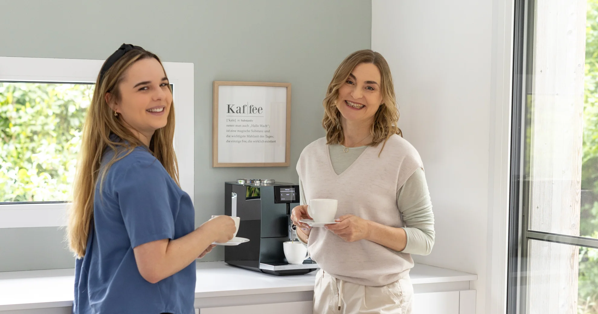 Zwei Frauen im Gespräch vor Kaffeemaschine – Symbol für Kontakt, Begegnung und Austausch